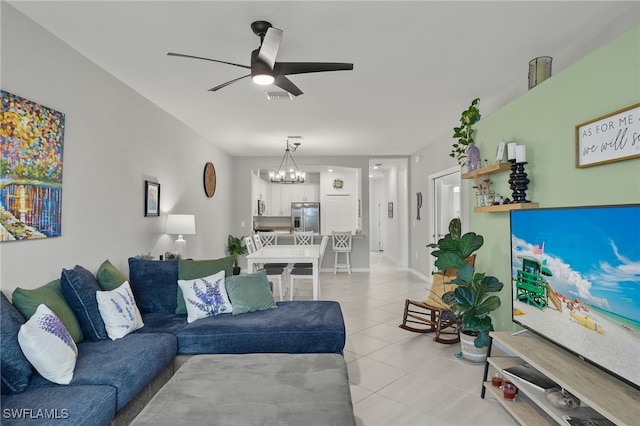 tiled living room with ceiling fan with notable chandelier