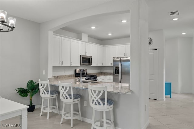 kitchen with a kitchen breakfast bar, white cabinets, kitchen peninsula, and stainless steel appliances