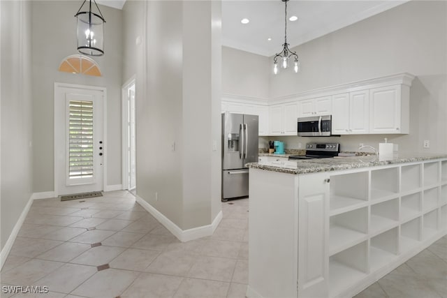 kitchen with white cabinets, a high ceiling, stainless steel appliances, and a chandelier