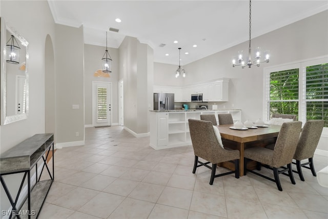 dining space featuring a towering ceiling, crown molding, light tile patterned floors, and an inviting chandelier