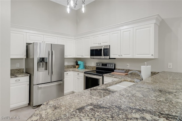 kitchen featuring light stone countertops, appliances with stainless steel finishes, sink, a notable chandelier, and white cabinets