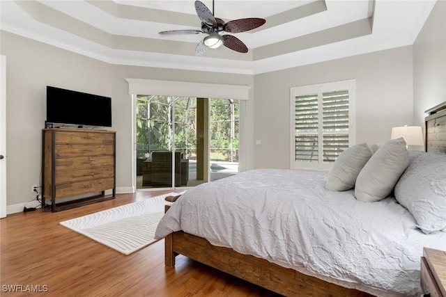 bedroom featuring a raised ceiling, access to exterior, ceiling fan, and hardwood / wood-style floors