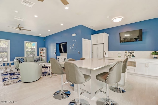 dining space with ceiling fan, sink, and light wood-type flooring