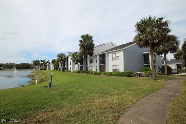 view of property's community with a water view and a lawn