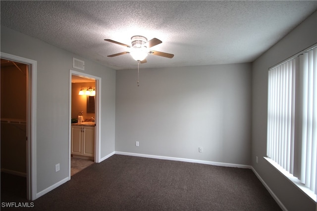 unfurnished bedroom with ceiling fan, a textured ceiling, a spacious closet, carpet floors, and a closet