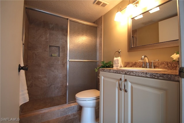 bathroom with a shower with door, vanity, a textured ceiling, and toilet