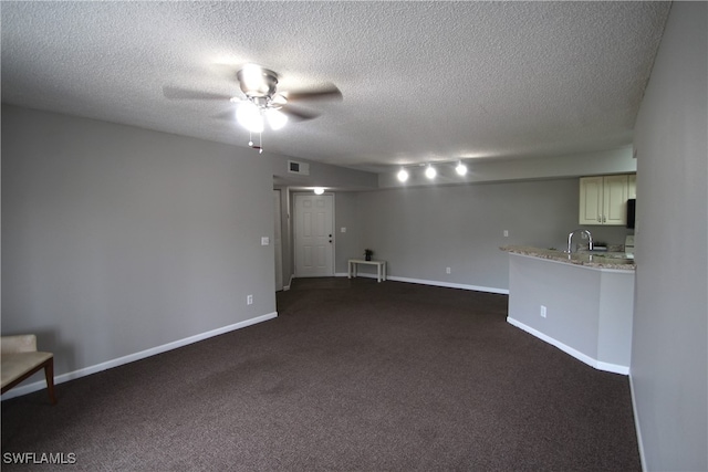 unfurnished living room featuring dark colored carpet, a textured ceiling, and ceiling fan