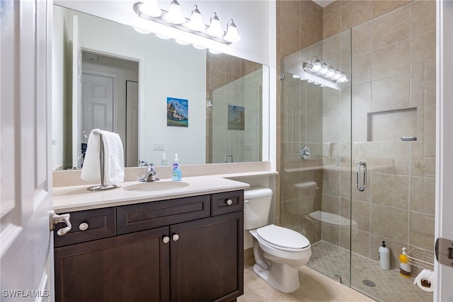 bathroom featuring toilet, a shower with shower door, vanity, and tile patterned flooring