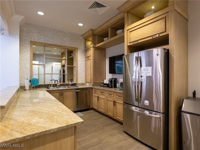 kitchen featuring kitchen peninsula, light stone countertops, sink, light hardwood / wood-style floors, and stainless steel appliances