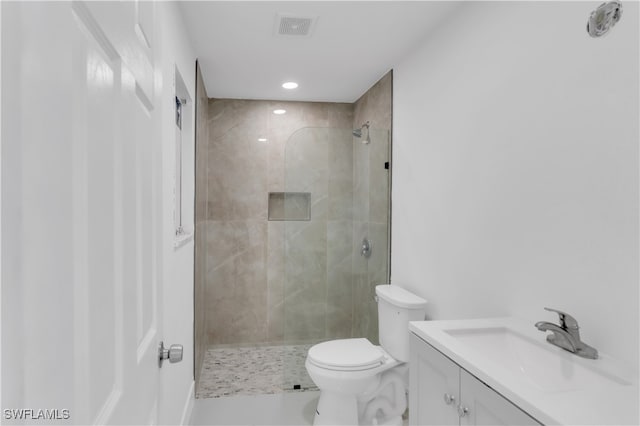 bathroom featuring tiled shower, vanity, and toilet