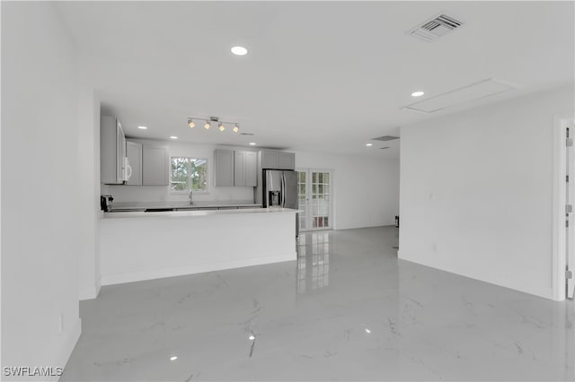 kitchen featuring kitchen peninsula, stainless steel fridge with ice dispenser, sink, and gray cabinetry