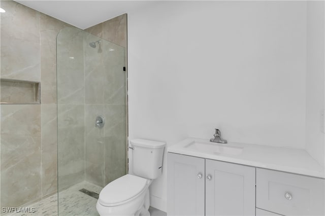 bathroom featuring a tile shower, vanity, and toilet