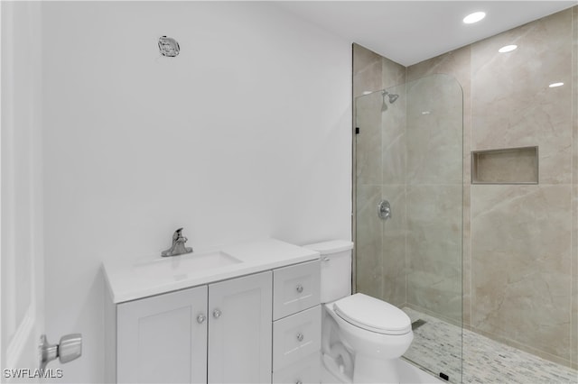 bathroom featuring a tile shower, vanity, and toilet