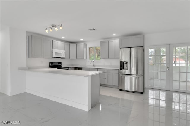 kitchen featuring a healthy amount of sunlight, stainless steel fridge with ice dispenser, kitchen peninsula, and black range with electric cooktop