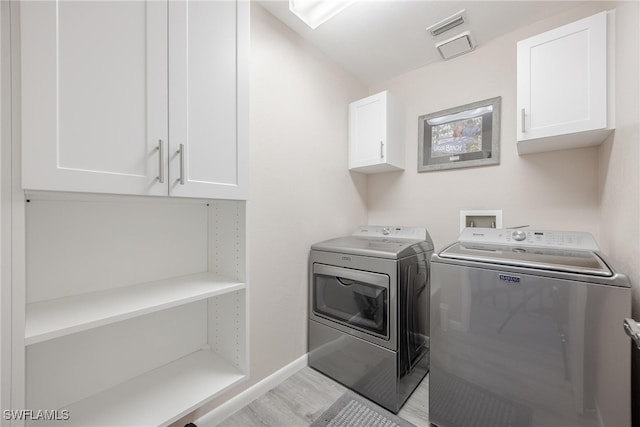 laundry area featuring light hardwood / wood-style flooring, washer and dryer, and cabinets