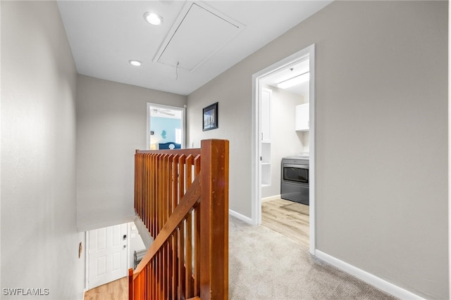 hallway with washer / dryer and light colored carpet