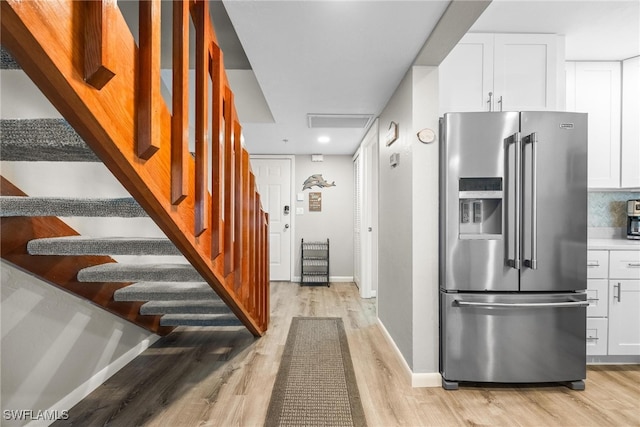 kitchen featuring stainless steel fridge, white cabinetry, and light hardwood / wood-style flooring