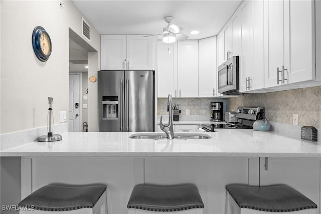 kitchen with appliances with stainless steel finishes, white cabinetry, and a kitchen breakfast bar