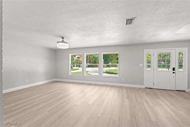 unfurnished living room featuring light hardwood / wood-style floors and a textured ceiling