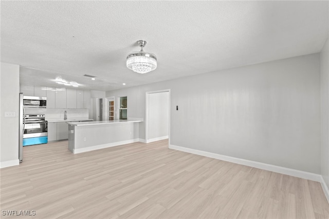 unfurnished living room featuring light hardwood / wood-style flooring and a textured ceiling