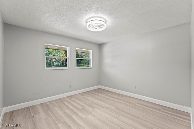 unfurnished room with a textured ceiling and light wood-type flooring