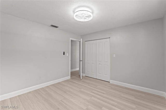 unfurnished bedroom with a closet, a textured ceiling, and light wood-type flooring