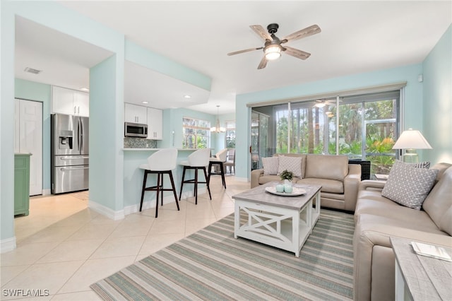 tiled living room featuring ceiling fan with notable chandelier