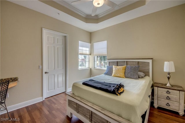 bedroom with a tray ceiling, baseboards, dark wood-type flooring, and a ceiling fan