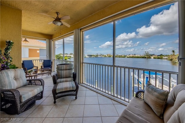 sunroom / solarium with ceiling fan and a water view