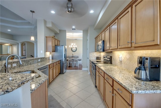 kitchen featuring tasteful backsplash, light stone countertops, decorative columns, appliances with stainless steel finishes, and a sink