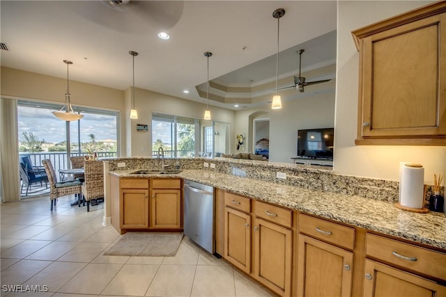 kitchen with light stone counters, a ceiling fan, a sink, stainless steel dishwasher, and a raised ceiling