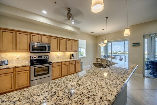 kitchen featuring tasteful backsplash, stainless steel appliances, ceiling fan, and a sink