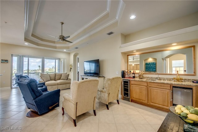 living room featuring light tile patterned floors, visible vents, a tray ceiling, wine cooler, and crown molding