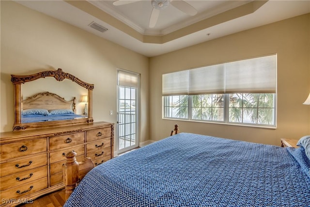 bedroom featuring wood finished floors, visible vents, a tray ceiling, ceiling fan, and ornamental molding