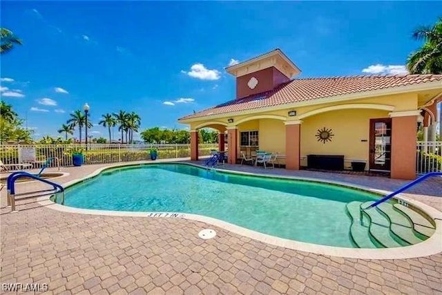 community pool with a patio area and fence