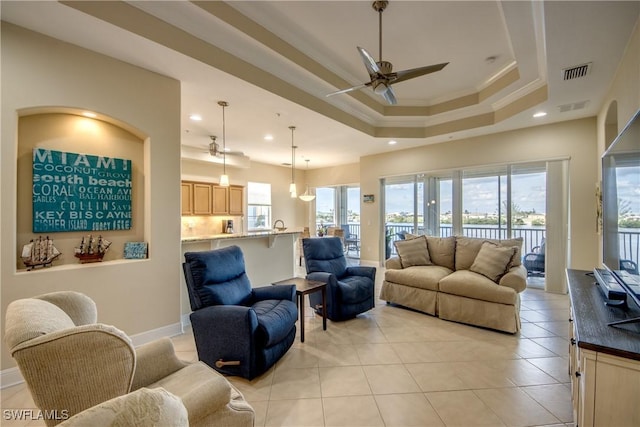 living room featuring a tray ceiling, plenty of natural light, visible vents, and ceiling fan