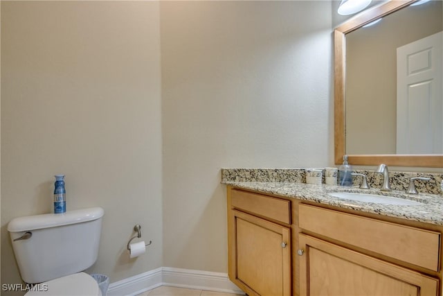 half bath featuring baseboards, toilet, and vanity