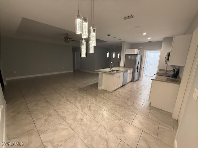 kitchen featuring stainless steel appliances, a sink, visible vents, open floor plan, and light stone countertops