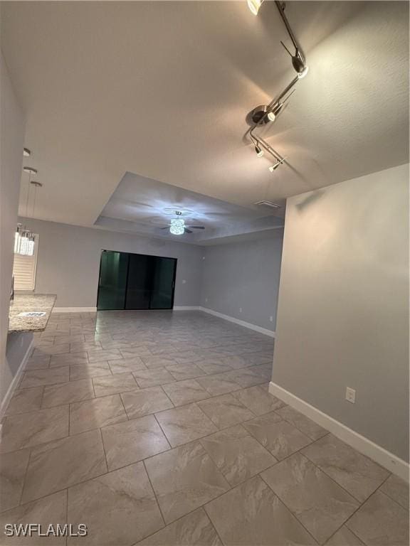 spare room featuring ceiling fan, rail lighting, and baseboards