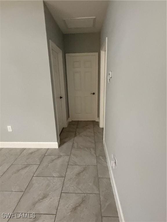 corridor with marble finish floor, attic access, and baseboards