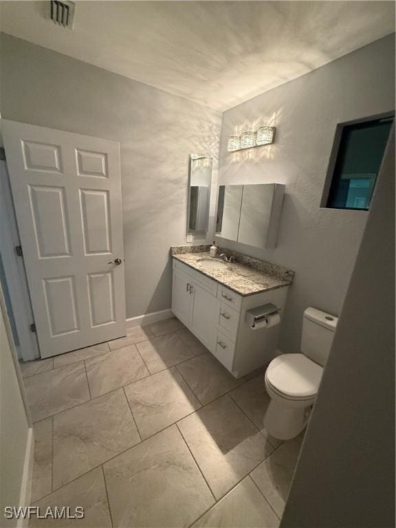 bathroom featuring toilet, vanity, visible vents, baseboards, and marble finish floor