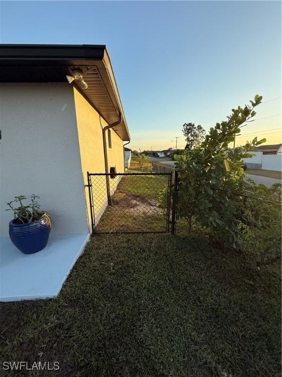 view of side of home featuring fence, a gate, and stucco siding