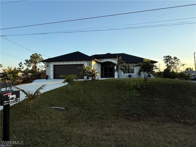 view of front facade with concrete driveway, a lawn, and an attached garage