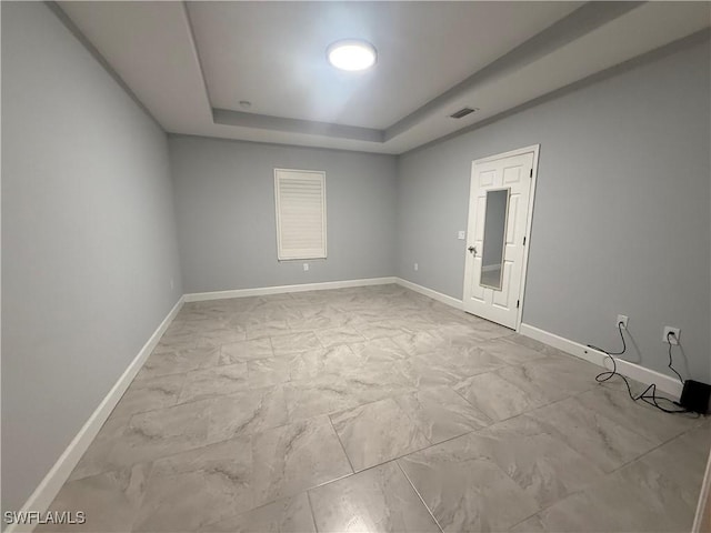 spare room featuring marble finish floor, visible vents, baseboards, and a raised ceiling