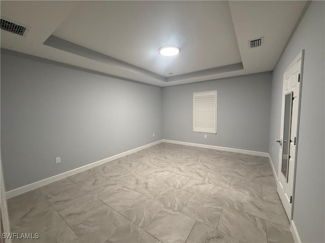 spare room featuring a raised ceiling, visible vents, marble finish floor, and baseboards