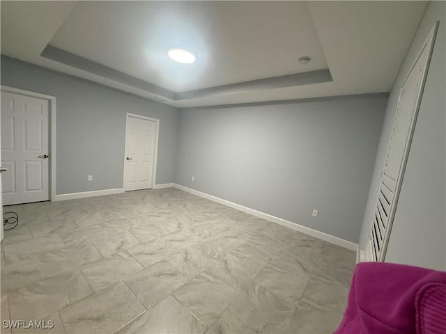 bedroom with marble finish floor, baseboards, and a tray ceiling