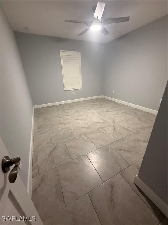 unfurnished room featuring marble finish floor, baseboards, and a ceiling fan