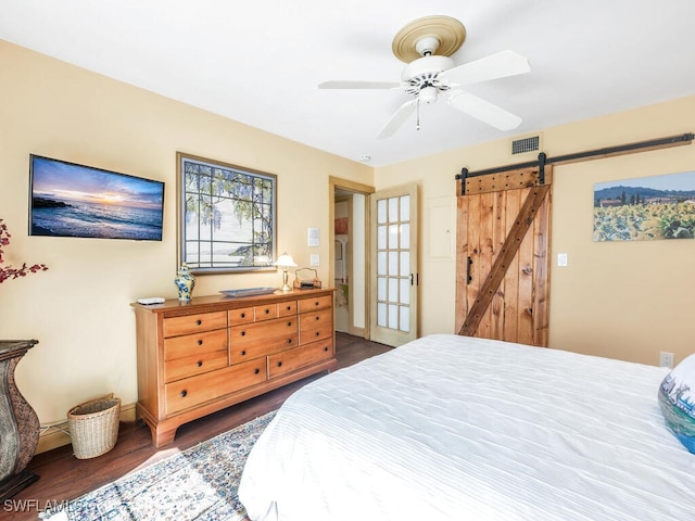 bedroom with dark hardwood / wood-style floors, a barn door, and ceiling fan