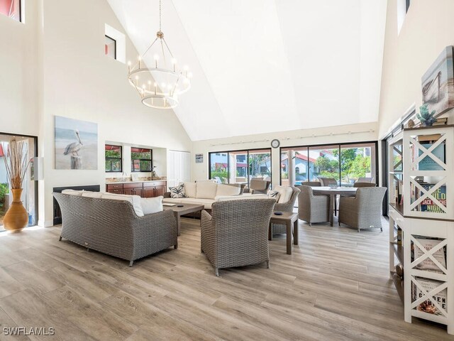 living room featuring high vaulted ceiling, a chandelier, and light hardwood / wood-style flooring