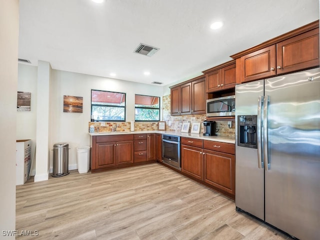 kitchen with stainless steel appliances, sink, backsplash, and light hardwood / wood-style floors